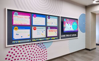 A wall with multiple bulletin boards displaying local attractions, bars, restaurants, shopping, and news.