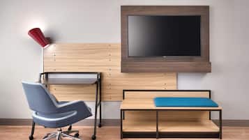 A modern office space with a desk, chair, and a mounted TV.