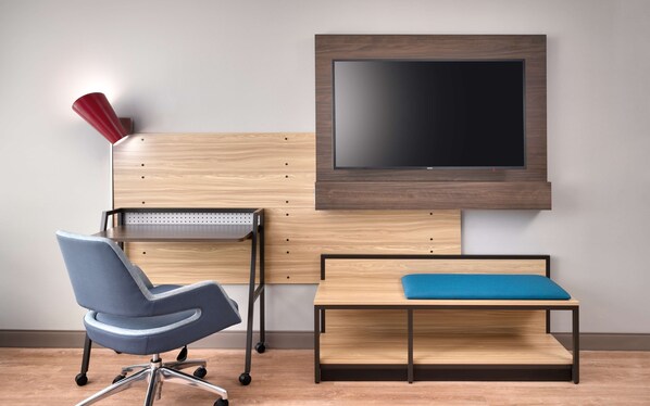 A modern office space with a desk, chair, and a mounted TV.