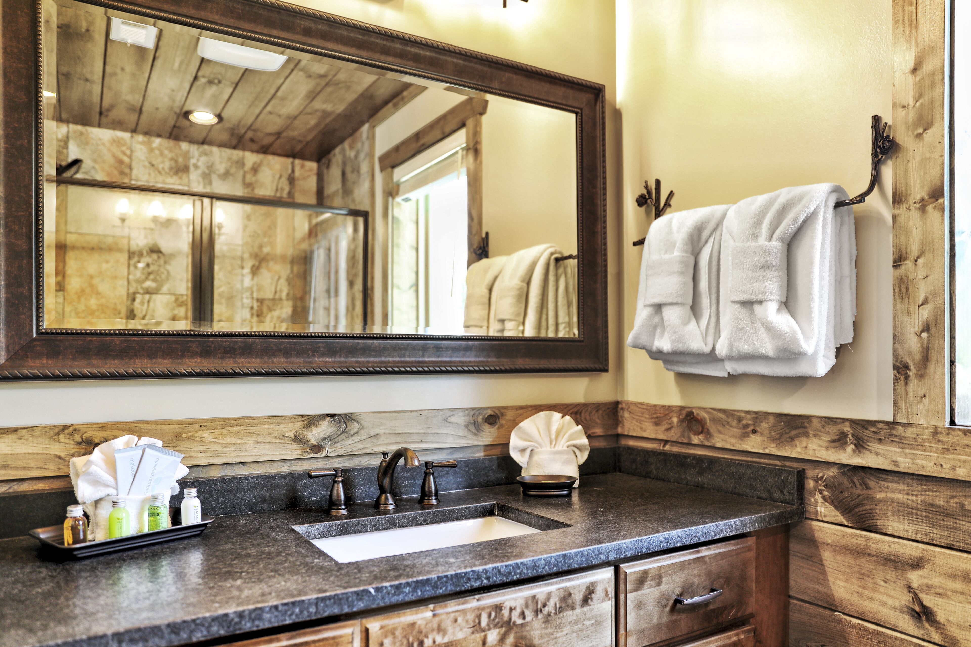 A bathroom with a wooden vanity, a sink, and a large mirror.