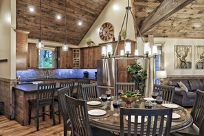 A spacious kitchen with wooden cabinets, a central island, and a dining area with a round table and chairs.