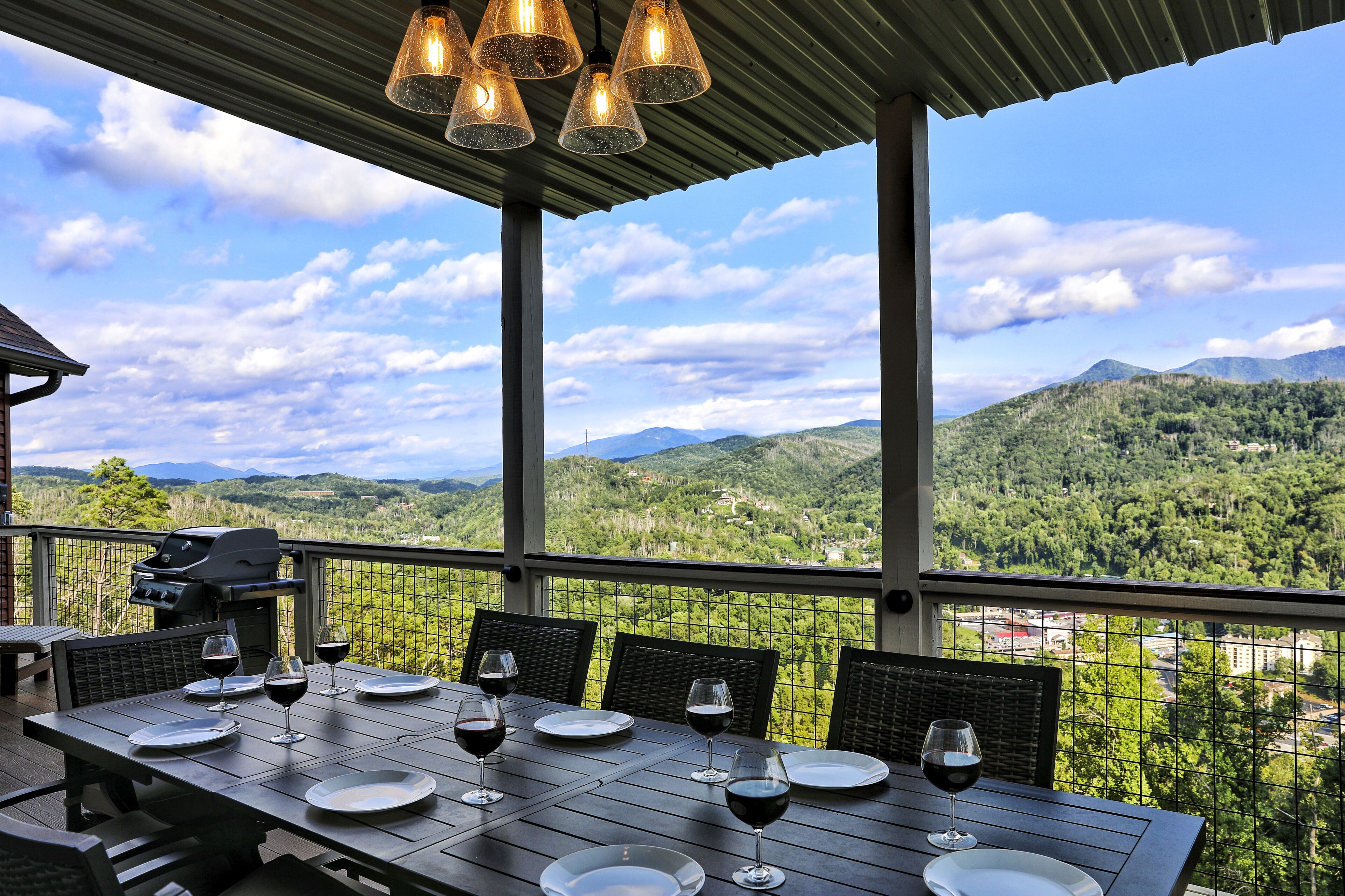 Un espace extérieur abrité, aménagé pour les repas, avec une table pour quatre personnes, un barbecue et une vue panoramique sur les montagnes.