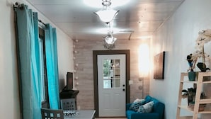 Un espace de vie compact comprenant un coin cuisine, un coin repas et un espace détente avec un canapé et une petite table.