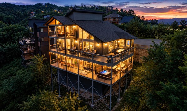 A multi-story house with a balcony and a hot tub, surrounded by trees.