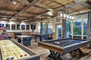 Une salle de billard dotée d’un parquet en bois, d’une table de billard et d’une table de jeu de palet.