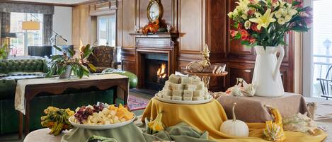 A dining area with a fireplace, a green sofa, and a table set with food and flowers.