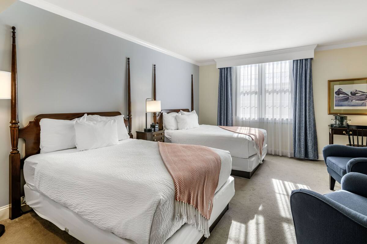 Habitación de hotel con dos camas, un escritorio y una silla.