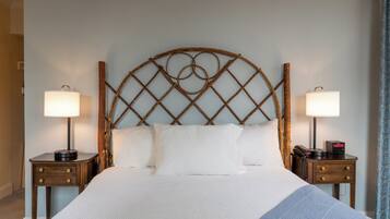 A neatly made bed with white bedding, two bedside tables with lamps, and a wooden headboard with a circular design.