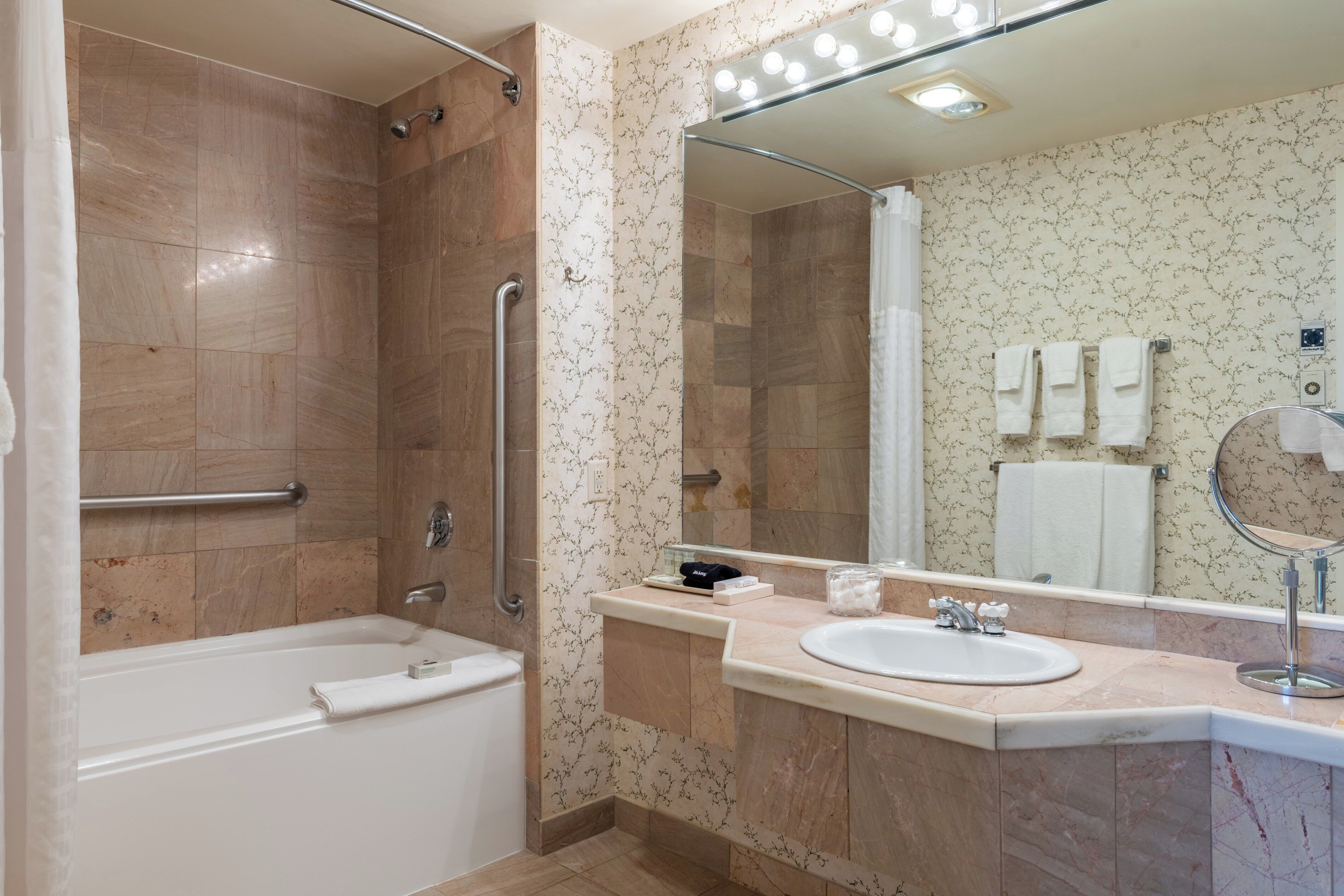A modern bathroom with a bathtub, a sink, a mirror, and a shower area.