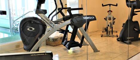 Un gimnasio con diversos equipos de ejercicio, incluyendo cintas de correr y bicicletas estáticas.