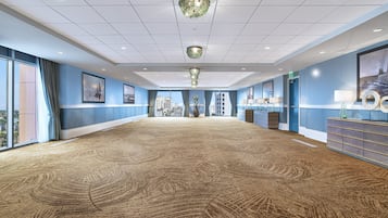 A spacious conference room with a patterned carpet, large windows, and a modern chandelier.