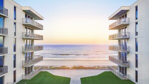 A modern building with multiple balconies overlooking a beach.