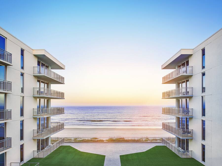 A modern building with multiple balconies overlooking a beach.