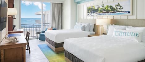 A hotel room with two beds, a desk, and a view of the ocean.
