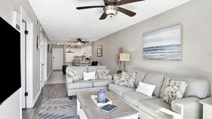 A modern living room with a grey sofa, a coffee table, and a ceiling fan.