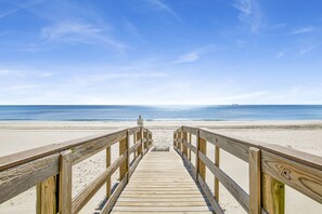 A wooden boardwalk leading to a beach with a clear sky. - 2BR @ Lei Lani Village • Sleeps 6 • Balcony, Pools & Easy Beach Access • Walk to Flora-Bama (Orange Beach)