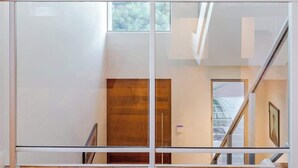 A modern interior with a glass railing, a wooden floor, and a hanging spherical light fixture. - La Vacanza—Luxe Spacious Home with Ocean Views (Dunsborough)