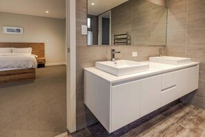 A modern bathroom with a large mirror, two sinks, and a wooden headboard in the adjacent bedroom. - La Vacanza—Luxe Spacious Home with Ocean Views (Dunsborough)