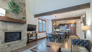 A spacious living room with a stone fireplace, a large dining table, and a leather sofa. - Family Retreat w/ Suncadia Pool Access (Cle Elum)
