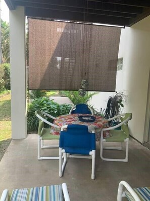 Eine Terrassengruppe mit Tisch und Stühlen, ein überdachter Bereich und Kübelpflanzen.