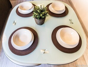 A dining table set with four bowls and a woven basket in the center, surrounded by a geometric patterned tablecloth.