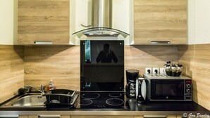 Una cuina moderna amb una campana d'extracció d'acer inoxidable, un microones integrat i una cafetera.