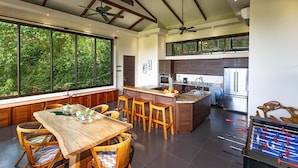 Una cocina moderna con una isla central, ventanas amplias y una mesa de futbolín.