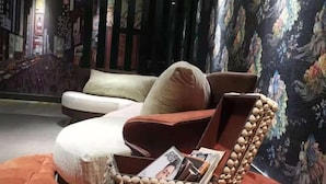Una sala moderna con un sofá, un reposapiés y una cesta de madera decorativa con revistas.