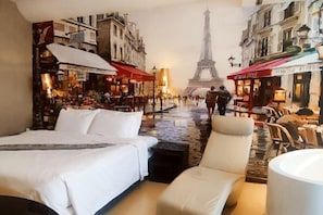 Habitación de hotel con cama, una silla y vista de la Torre Eiffel a través de un mural.
