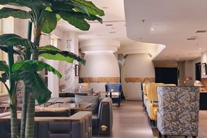 A modern hotel lobby with seating areas, large decorative columns, and a large plant. - Shenyang Le Grand V Hotel (Shenyang)