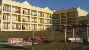 Um hotel com vários andares, varandas e uma área gramada com uma rede.