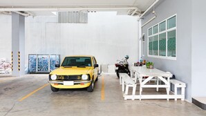 A yellow car parked in a garage with a white table and benches. - Udee Living Place (Hat Yai)
