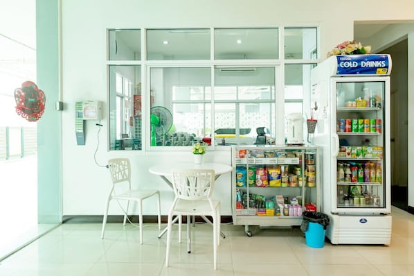 A room with a window, a fan, a table with chairs, and a refrigerator stocked with beverages.