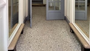 Ein Flur mit Fliesenboden, einer Tür mit Glasfeldern und einer Bank.