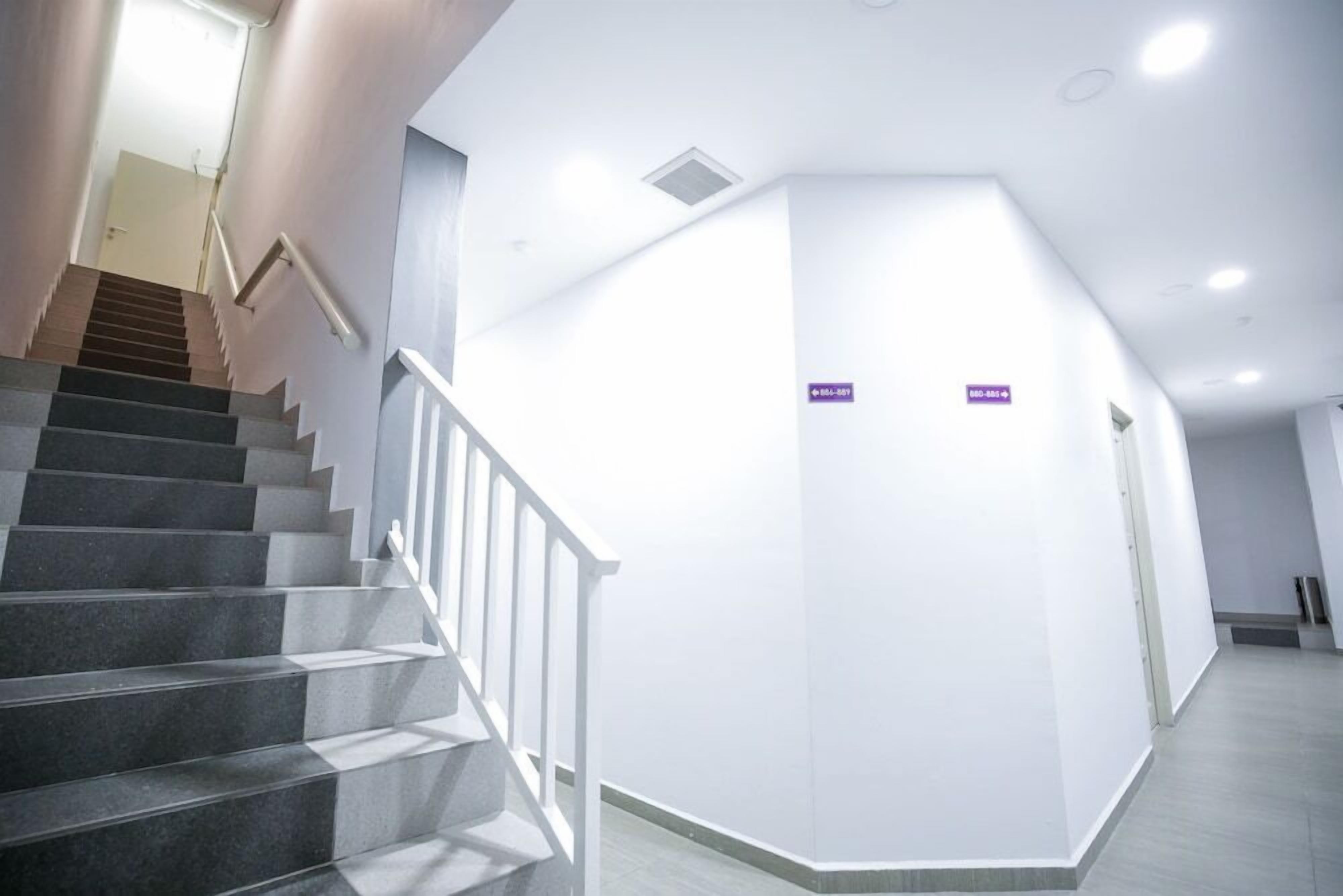 A modern interior with a staircase, white walls, and a sign indicating a room number.