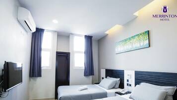 A Deluxe Twin room with two beds, a flat-screen TV, an air conditioner, and a painting on the wall.