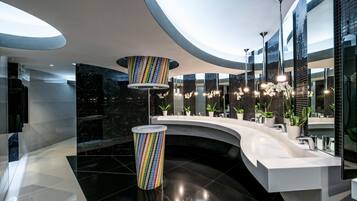 Bathroom features a sleek design with a curved sink counter, multiple mirrors, and a bathtub.