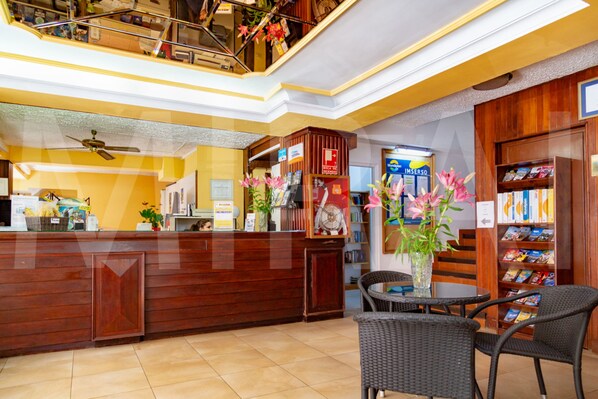 A reception area with a wooden counter, a staircase, and a seating area with a table and chairs. - Hotel Tropical (Puerto de la Cruz)