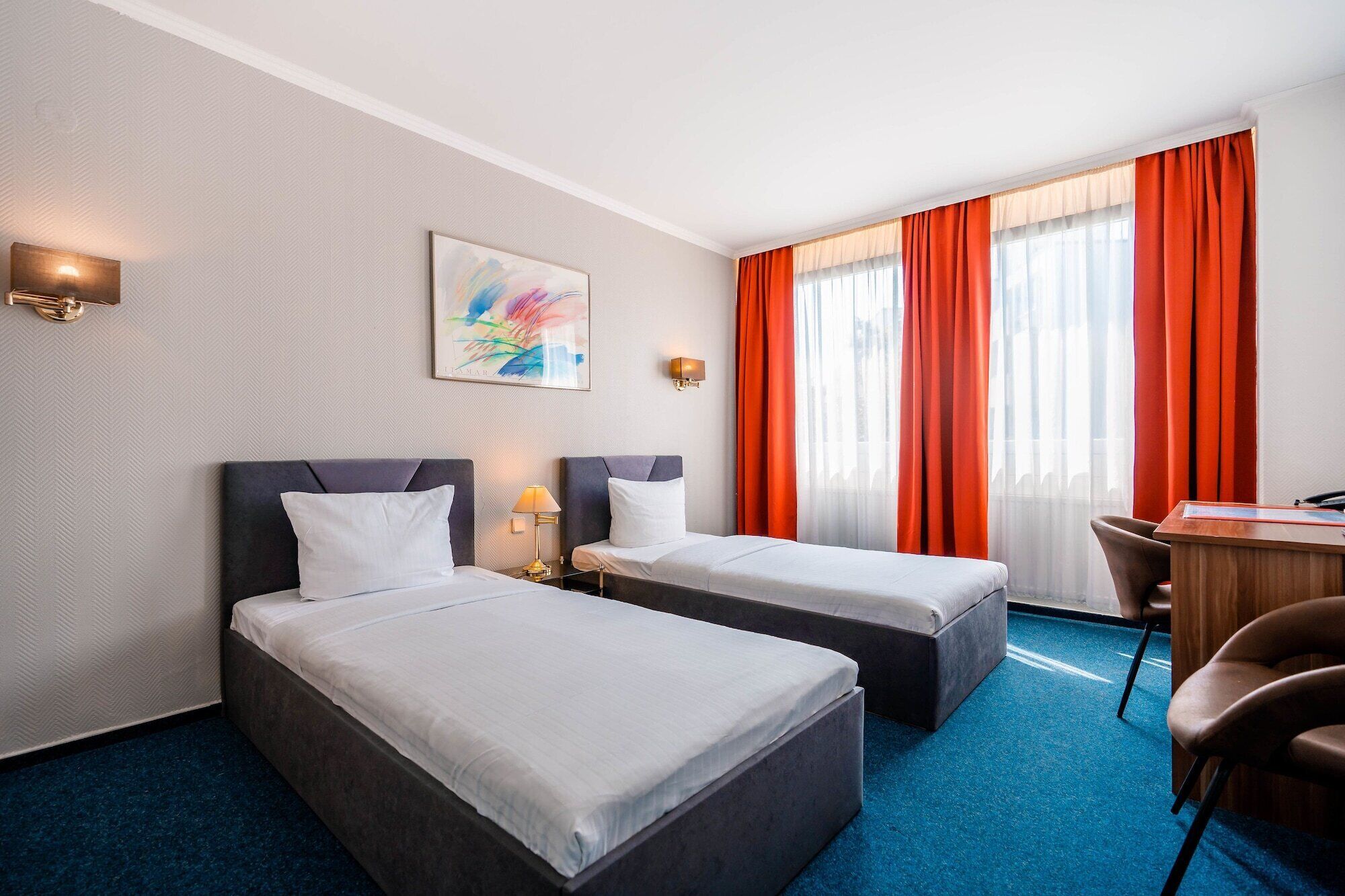 A hotel room with two beds, a desk, and a chair.