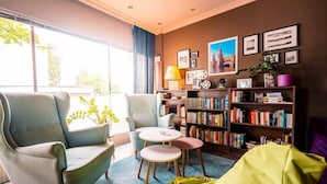 A cozy living room with a sofa, two armchairs, a small table, and a bookshelf filled with books. - Berliner Baer (Berlin)