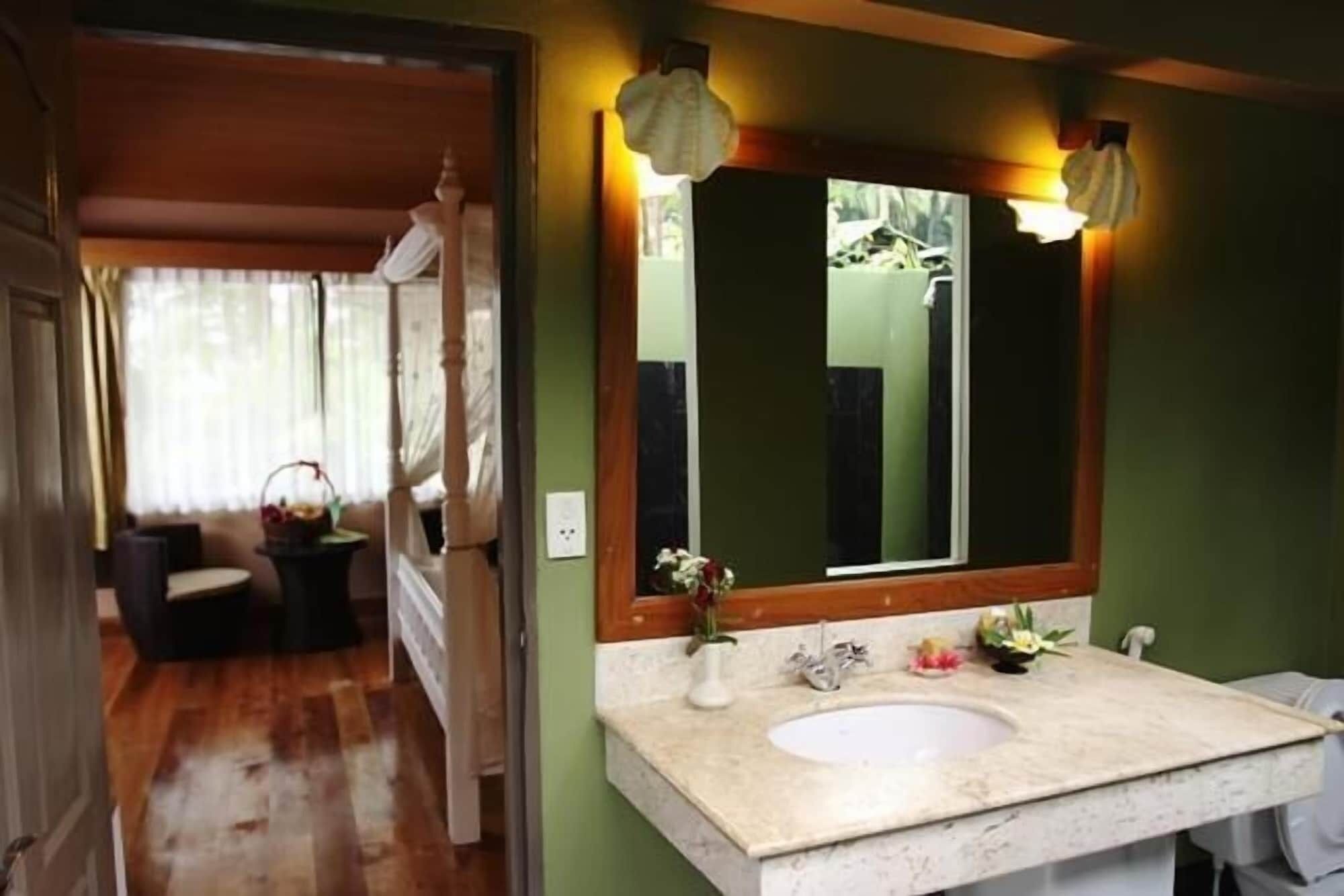 A bathroom with a large mirror, a sink, and a shower area.