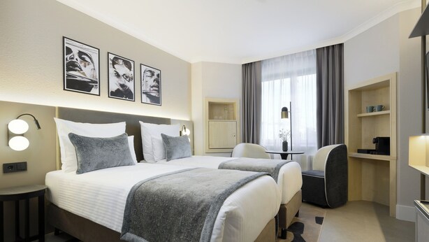 Une chambre d’hôtel avec un grand lit, deux tables de chevet, un bureau, une chaise et une armoire.