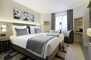 A hotel room with a large bed, two bedside tables, a desk, a chair, and a wardrobe. - Leonardo Hotel Nürnberg City Center (Nuremberg)