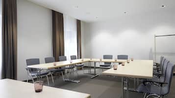 Un salón de conferencias con una larga mesa, sillas y una pizarra.