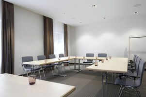 Un salón de conferencias con una larga mesa, sillas y una pizarra.