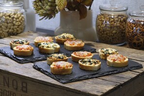 Una mesa de madera con varios panecillos redondos tostados, cubiertos con diferentes ingredientes.