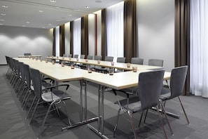 A conference room with a long table, multiple chairs, and a modern ceiling design. - Leonardo Hotel Nürnberg City Center (Nuremberg)