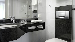 Une salle de bain moderne avec un plan de toilette noir, un lavabo blanc, une douche en verre et un porte-serviettes.