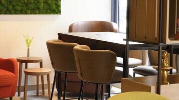 Un interior moderno con zona de comedor, dos sillas, una mesita y una planta decorativa.