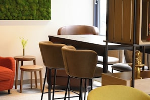 Ein modernes Interieur mit Essbereich, zwei Stühlen, einem kleinen Tisch und einer Zierpflanze.